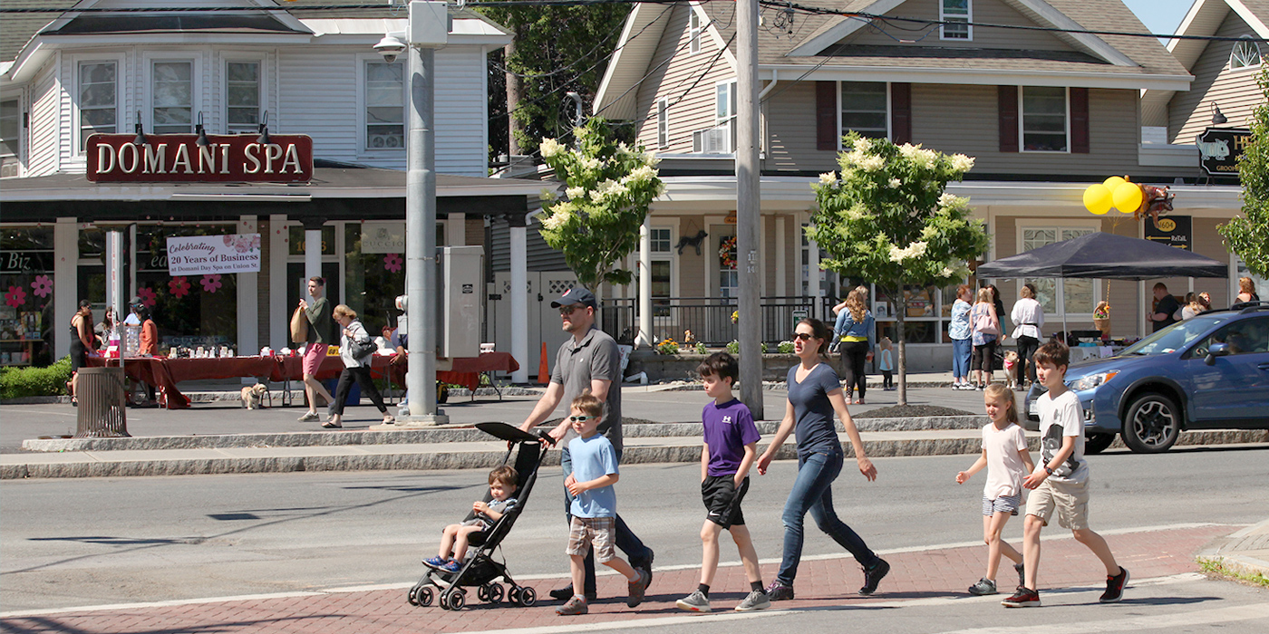 family walking down Upper Union Street in front of people and businesses